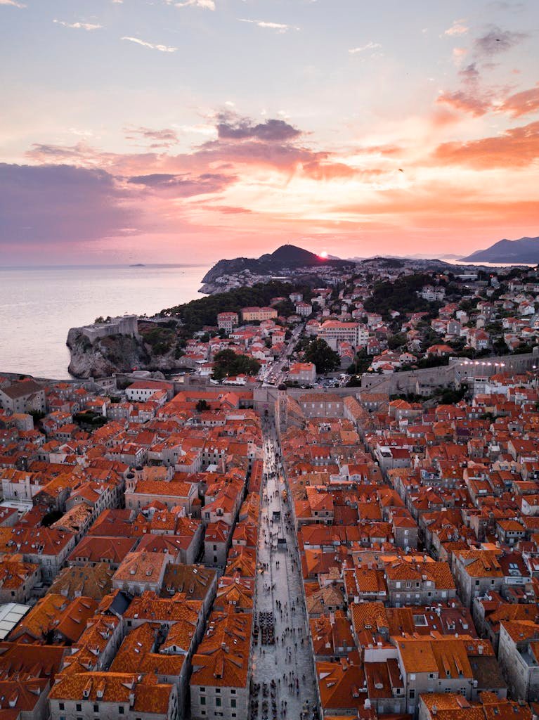 Unlocking the Western Balkans Embrace the deep cultural experiences and affordable joy of slow travel Balkans. Stunning aerial view of Dubrovnik's Old Town with red rooftops and sunset sky over the Adriatic Sea.